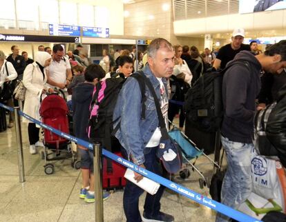 Los refugiados forman una fila frente a los mostradores de facturación del aeropuerto ateniense.