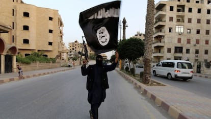 Un miembro de Daesh muestra una bandera del Estado Isl&aacute;mico en Raqqa, en una fotograf&iacute;a de archivo.