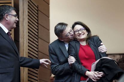 El presidente de la Generalitat valenciana, Ximo Puig, abraza a la vicepresidenta, Mónica Oltra, ante el presidente de las Cortes, Enric Morera.