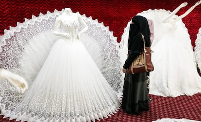 Una mujer yemení con un niqab mira un vestido de boda en Saná.