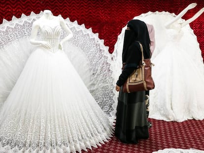 Una mujer yemení con un niqab mira un vestido de boda en Saná.