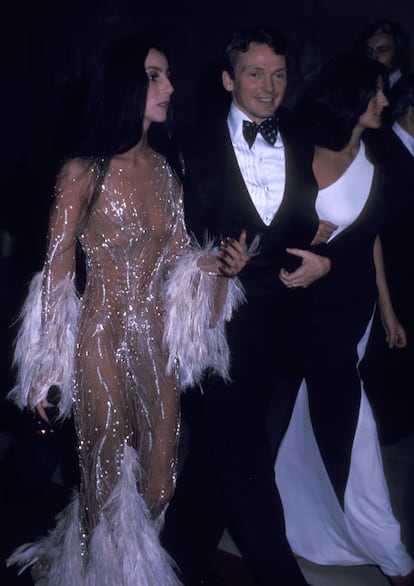 El vestido desnudo de Cher (1974). La aparición de la intérprete de Believe a mediados de los 70 fue tan sorprendente como adelantada a su tiempo. Mucho antes de que los naked dress o vestidos desnudos fueran tendencia en las alfombras rojas, Cher se plantó en la noche en la que se inauguraba la exposición 'Romantic and Glamorous Hollywood Design' llevando un vestido de Bob Mackie de plumas, transparencias y brillos que dejaba intuir perfectamente su escultural anatomía bajo la tela.