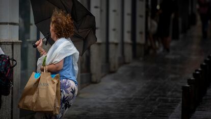 Una mujer sujeta su paraguas este domingo en el distrito de Usera, en el suroeste de Madrid.