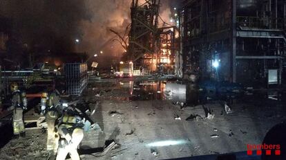 Los bomberos han informado de que durante toda la noche, los efectivos de treinta dotaciones han seguido trabajando en las instalaciones de Industrias Químicas del Óxido de Etileno (IQOXE), situada en La Canonja. En la imagen, un grupo de bomberos trabaja en el interior de la empresa petroquímica tras la explosión, este martes.