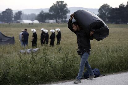 Un refugiado carga con sus pertenencias durante la operación policial en un campamento de refugiados improvisado en la frontera de Macedonia con Grecia, cerca de Idomeni.