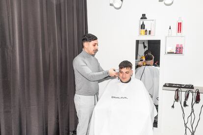 Manuel Romario corta el pelo a un cliente en su peluquería de la zona norte de Granada.
