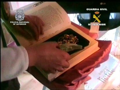 Un agente muestra piezas arqueológicas ocultas en un libro.