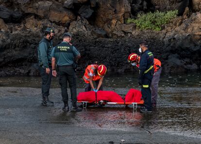 El personal de los servicios de emergencia y los agentes de la Guardia Civil junto a un cuerpo sin vida de uno de los migrantes que iban a bordo de la patera naufragada este martes por la noche cerca del muelle de Órzola, en Lanzarote. 