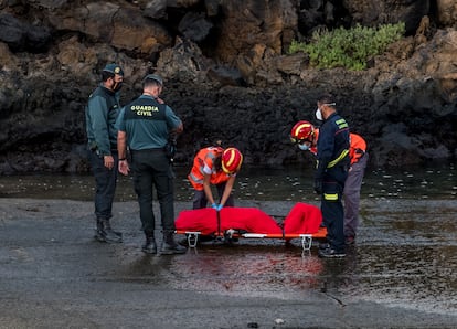 El personal de los servicios de emergencia y los agentes de la Guardia Civil junto a un cuerpo sin vida de uno de los migrantes que iban a bordo de la patera naufragada este martes por la noche cerca del muelle de Órzola, en Lanzarote. 