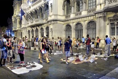 Un grupo de <i>manteros</i> ofreciendo sus productos frente al Moll de la Fusta, el miércoles por la noche.