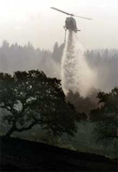 Un helicóptero lanza agua sobre la localidad onubense de Minas de Río Tinto.