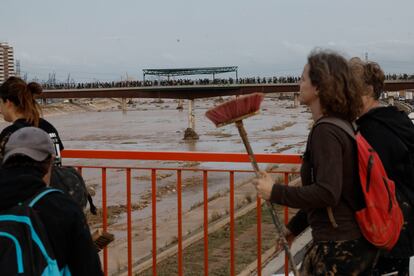 Numerosos voluntarios cruzan un puente para ayudar a las zonas afectadas por el temporal en Valencia.