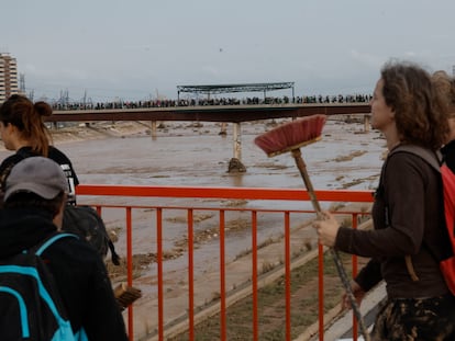 Numerosos voluntarios cruzan un puente para ayudar a las zonas afectadas por el temporal en Valencia.