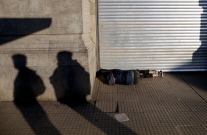 Un hombre duerme junto a una tienda cerrada durante la huelga de 24 horas que ha paralizado el país.