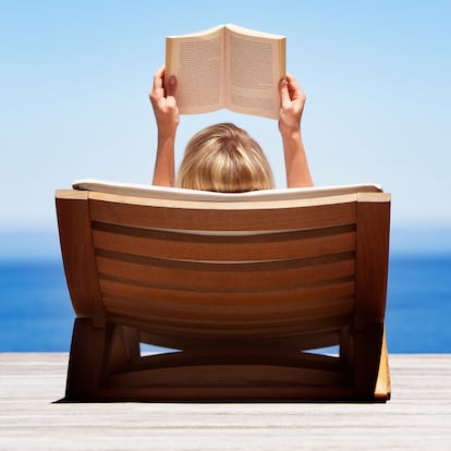 Rear view of woman reading outdoors in wooden chair