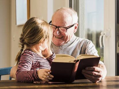 Un hombre lee un libro con su nieta.