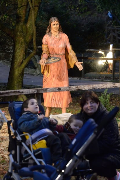 Una familia posa delante de una figura que representa una campesina dando de comer a unas gallinas. 