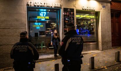 Una pareja de policías municipales controla el cierre de los bares de la zona de La Latina, en el centro de Madrid, primera noche de toque de queda.