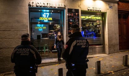 Una pareja de policías municipales controla el cierre de los bares de la zona de La Latina, en el centro de Madrid, primera noche de toque de queda.