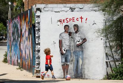 Un niño juega con una pelota junto a un mural de Lamine Yamal y Nico Williams en Barcelona.