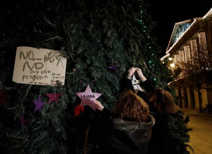 Dos mujeres colocan en un árbol de Navidad de la Plaza del Castillo en Pamplona dos estrellas, una de ellas con el nombre de Laura Luelmo y la otra con el numero de mujeres asesinadas este año.