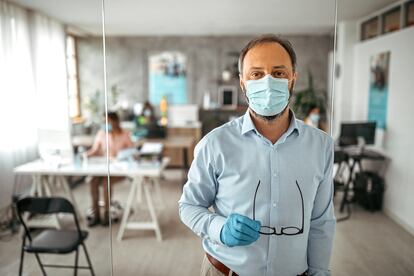Businessman with protective gloves and face mask at office