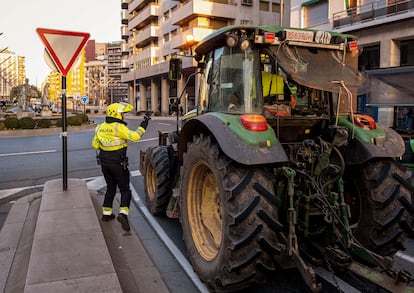 Un agente de policía local conversa con un agricultor que circula en su tractor por una calle de Logroño, este miércoles.