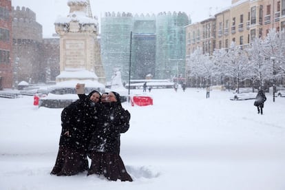 Tres monjas se hacen un selfi en el Mercado Grande de Ávila durante la nevada que cubre la ciudad. 