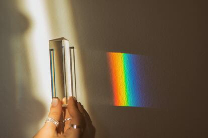 Una persona sostiene un prisma óptico que refleja el arcoíris.