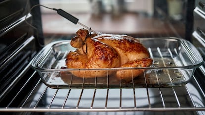 Pollo asado con un termómetro que está midiendo su temperatura interna.