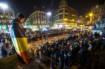 Un hombre envuelto en una bandera belga sostiene una vela mientras la gente se reúne en un monumento improvisado frente a la Bolsa de Bruselas en la Place de la Bourse el 24 de marzo de 2016, en Bruselas (Bélgica).