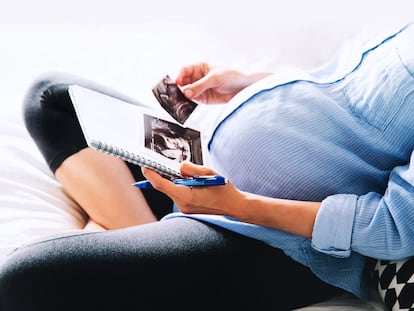 Una mujer embarazada sostiene una ecografía.