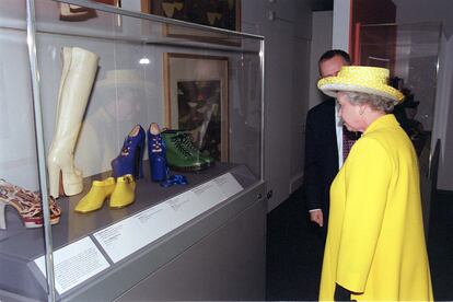 La reina Isabel II mira un par de zapatos de plataforma azúl diseñados por Vivienne Westwood durante una exposición en el Museo Victoria y Alberto, en Londres. Los zapatos que mira son los que llevaba la modelo Naomi Campbell cuando se tropezó en una pasarela de París, en 1993.