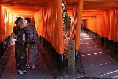 Mujeres vestidas con kimonos se toman una fotografía, en el santuario Fushimi Inari Taish, en Kioto (Japón). 