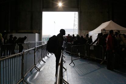 Varios migrantes esperan para coger uno de los autobús tras desalojar el campamento de Calais.