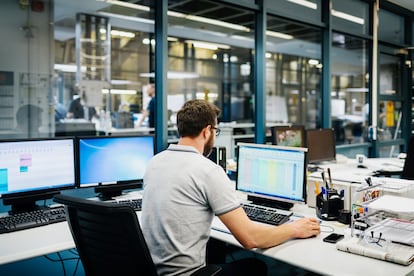 Engineer in a factory control room working on multiple computers.