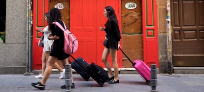 Tres jóvenes turistas llevan sus maletas por la calle de las Maldonadas de Madrid.
