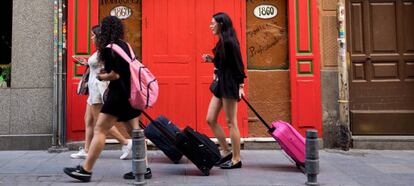 Tres jóvenes turistas llevan sus maletas por la calle de las Maldonadas de Madrid.