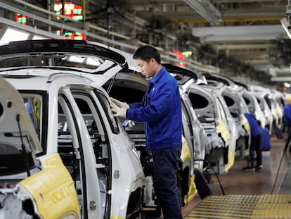 Varios trabajadores ensamblan distintas partes de coches eléctricos en la fábrica de General Motors en Liuzhou, en China, en febrero de 2019.