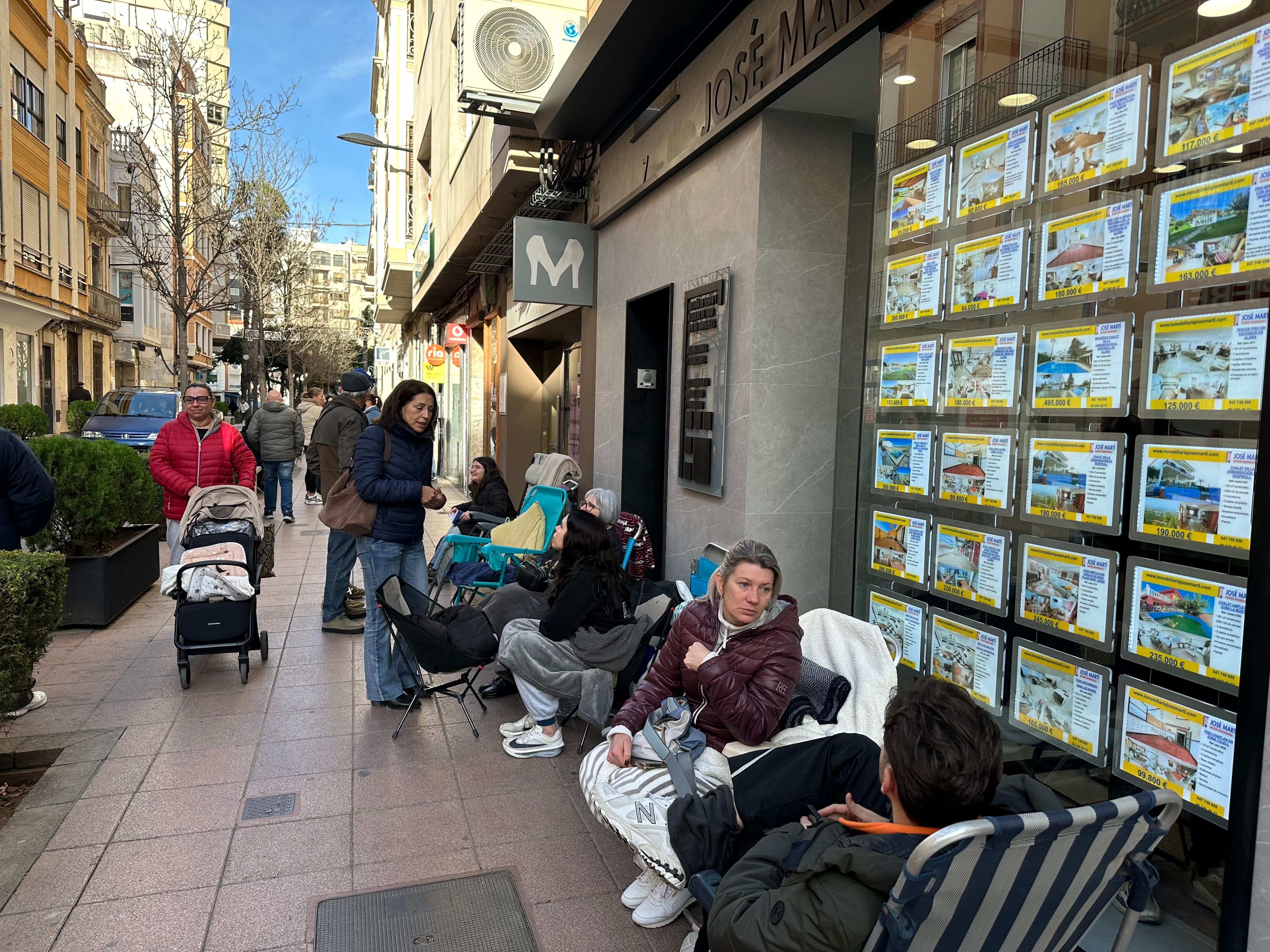 Varias personas hacen cola ante una inmobiliaria de Alzira (Valencia) para asegurarse una vivienda de promoción pública.