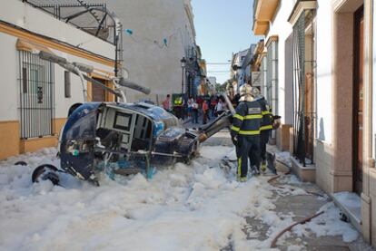 Los bomberos, junto al helicóptero caído ayer contra la valla de una iglesia.