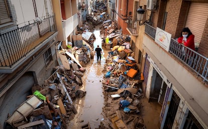 People walk through a street with piled furniture and rubbish in Paiporta, Valencia, on November 5.