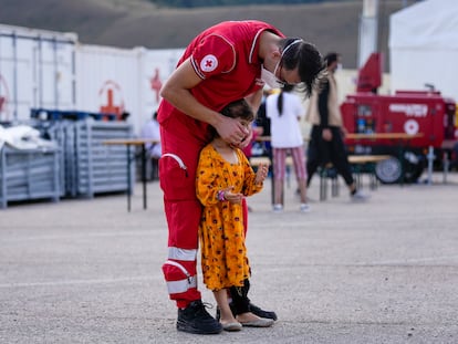 Un trabajador de Cruz Roja con un niño afgano en un campo de refugiados en Avezzano, Italia, el 31 de agosto.