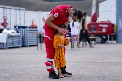 Un trabajador de Cruz Roja con un niño afgano en un campo de refugiados en Avezzano, Italia, el 31 de agosto.