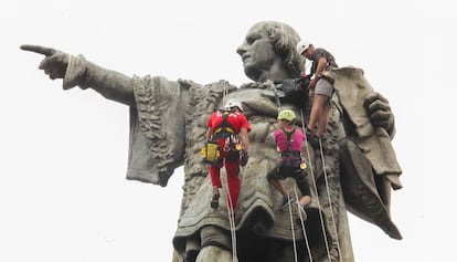 Tres escaladores en la estatua de Cristóbal Colón