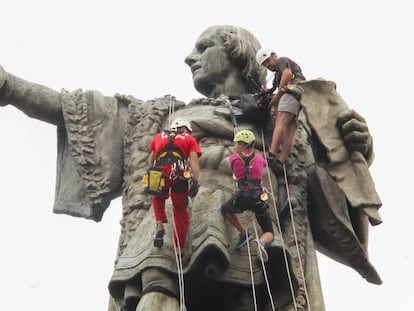 Tres escaladors a l'estàtua de Colom.