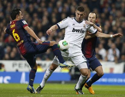 Karim Benzema pelea un balón con Xavi Hernández y Andrés Iniesta.