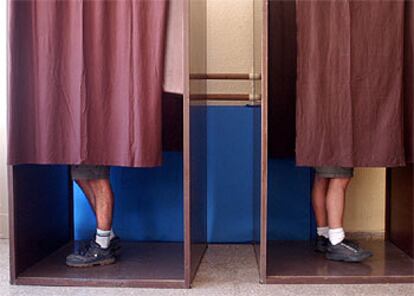 Dos montañeros preparan sus papeletas dentro de la cabina en un colegio electoral de Valencia.