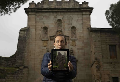 Mario Cuéllar  delante del pórtico del Monasterio de Santa Maria la Real de Valdeiglesias, con la foto de la escultura que ha localizado en una finca en Toledo.