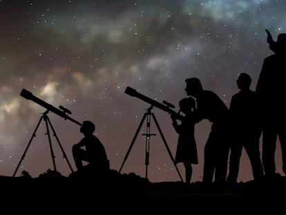 Un grupo de personas mira las estrellas con telescopios.